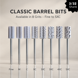 Set of eight cylindrical metal carbide bits with different grits on a beige background for nail technician professional use